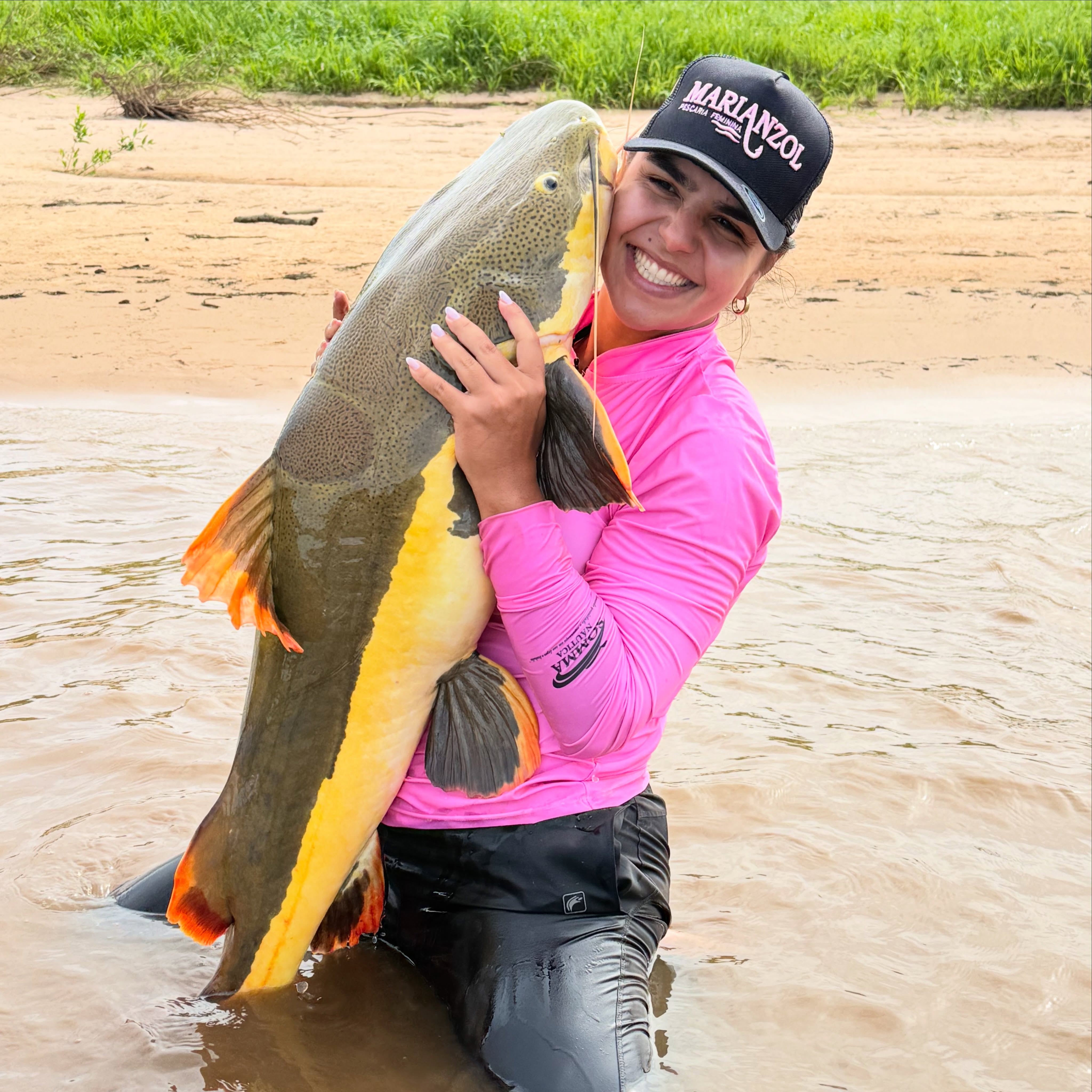 Pescadora de camiseta rosa segurando um peixe