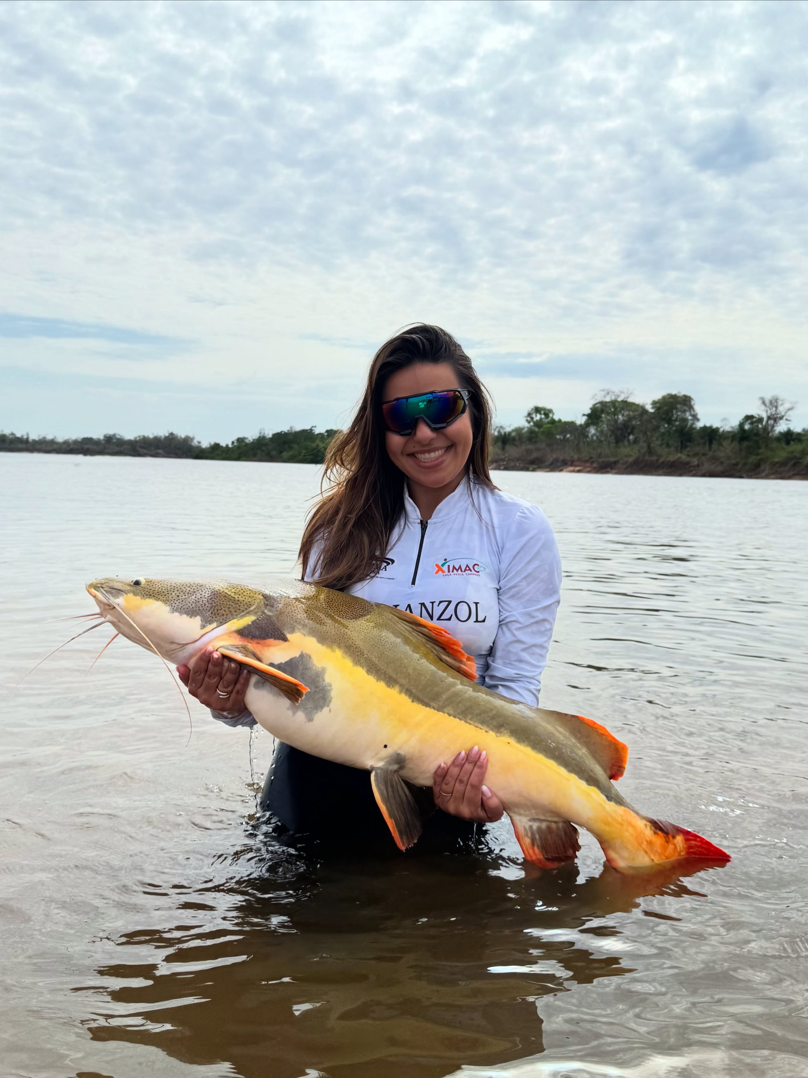 Pescadora na água com um peixe grande