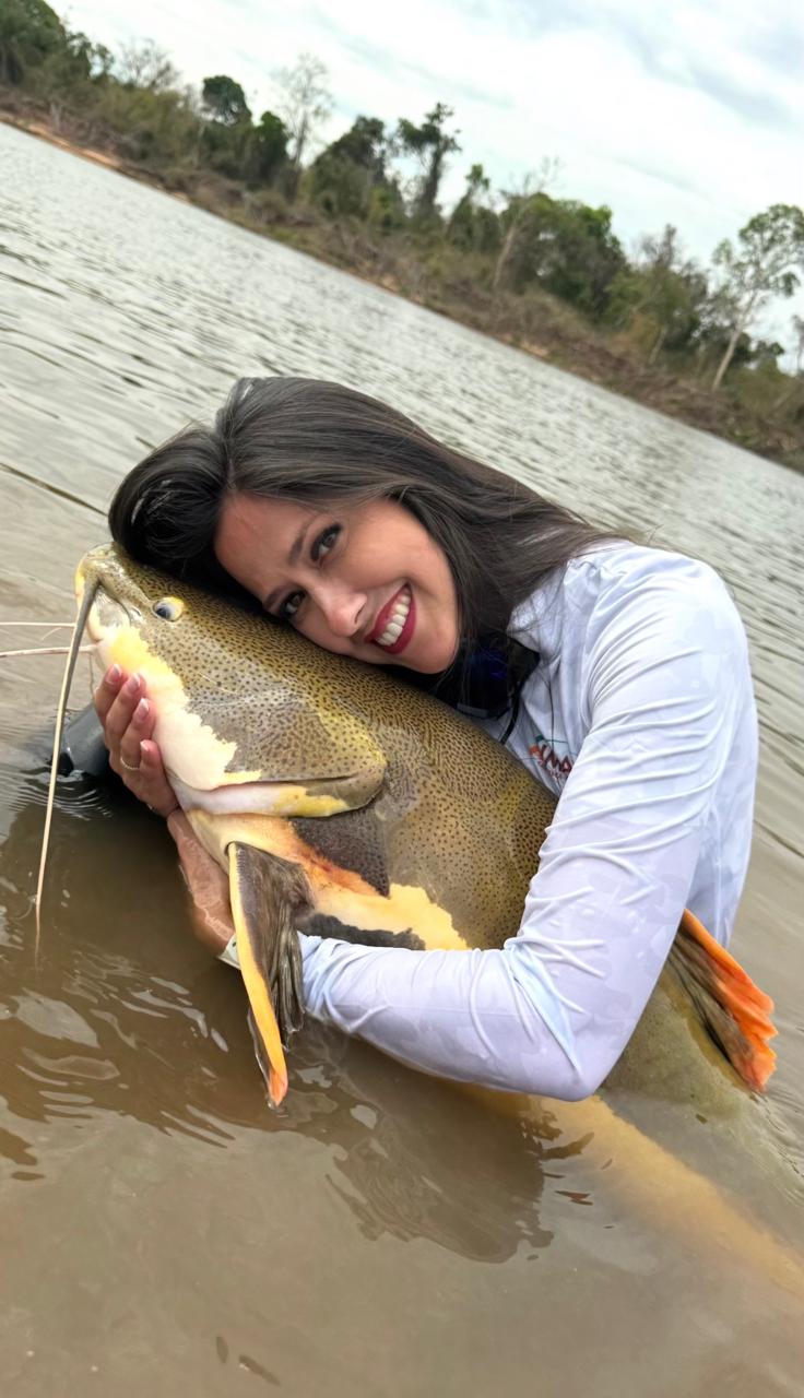 Pescadora da Marianzol abraçando um peixe no rio